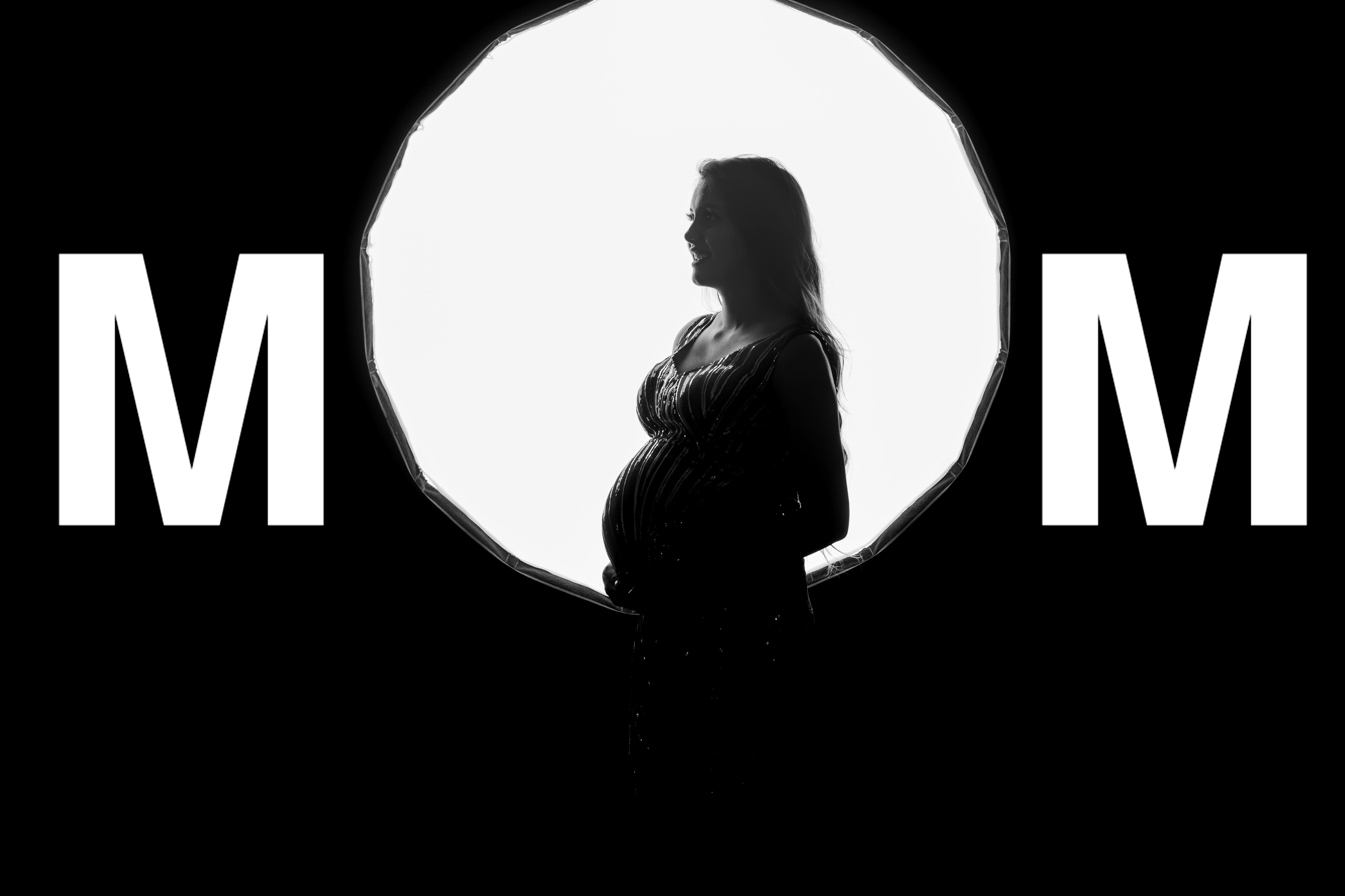 Pregnant woman in an elegant black-and-white maternity pose, celebrating her baby bump.